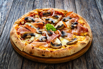 Pizza speck with ham, mozzarella cheese and white mushrooms on wooden table
