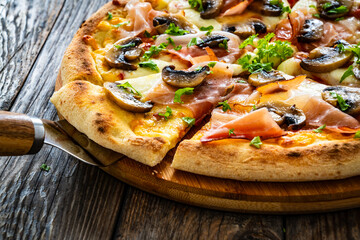 Pizza speck with ham, mozzarella cheese and white mushrooms on wooden table
