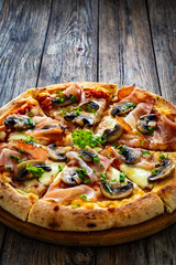 Pizza speck with ham, mozzarella cheese and white mushrooms on wooden table

