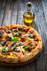 Pizza speck with ham, mozzarella cheese and white mushrooms on wooden table
