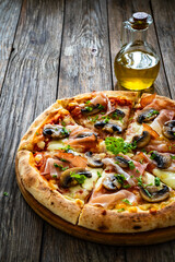 Pizza speck with ham, mozzarella cheese and white mushrooms on wooden table
