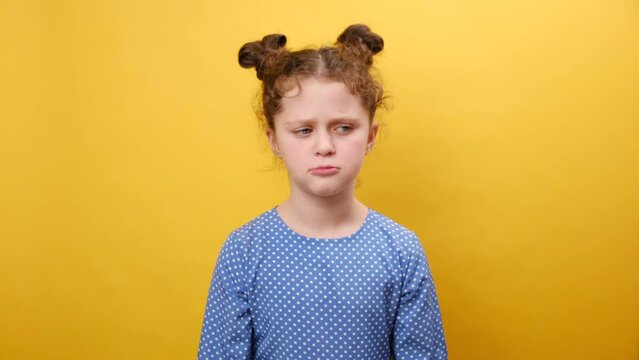 Misbehavior and childhood concept. Portrait of naughty upset little caucasian girl child sulking and grimacing expressing discontent, posing isolated over plain yellow color background wall in studio