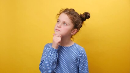 Hmm, let's think. Portrait of thoughtful little girl kid contemplating about idea, touching her chin, posing isolated over plain yellow color background wall in studio. Pensive and brainstorm concept