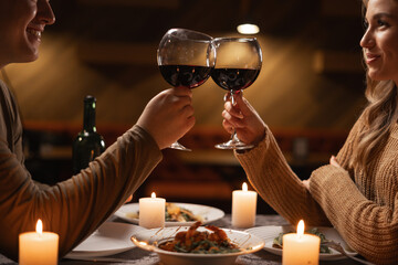 Happy young couple in love drinking wine and clinking glasses having romantic dinner - obrazy, fototapety, plakaty
