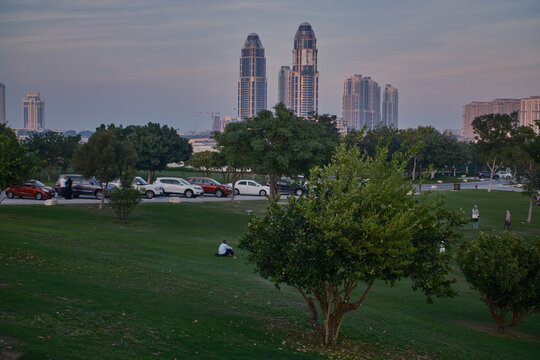 UDC tower and the pearl skyline , from Katara hills in Doha, Qatar sunset shot with trees in foreground and clouds in the sky in background