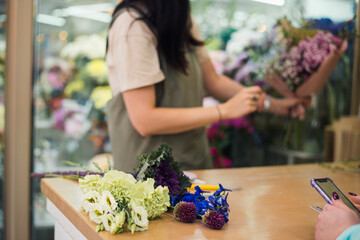 young woman florist making bouquet fresh flowers, flower shop business, no face