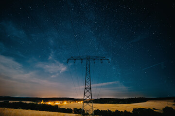 mast of a high-voltage power line on a summer night against the backdrop of stars
