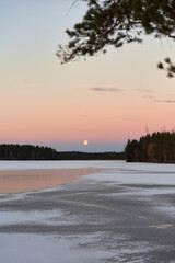 blue hour and moon rise on a lake in winter