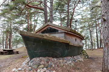 
An old boat placed in the forest among the trees and made with a roof for viewing