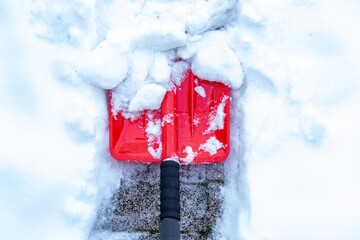 Snow removal in winter, Snowfall, Red shovel lying in the snow. Seasonal concept, difficult weather conditions - obrazy, fototapety, plakaty