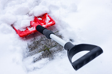 Snow removal in winter, Snowfall, Red shovel lying in the snow. Seasonal concept, difficult weather...