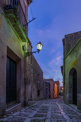 A characteristic alley of the Erice medieval town at nightfall, Sicily  - 690751192