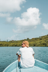 Fototapeta premium Man with cap and sunglasses sitting on the edge of a boat floating
