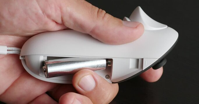 Close-up of male hands changes battery in wireless joystick for VR headset.