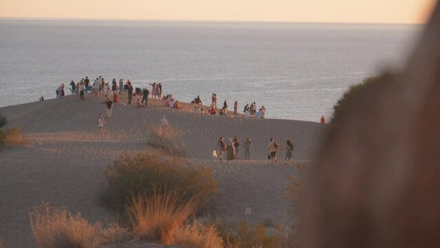 PATARA, TURKEY - SEPTEMBER 2, 2023: Large number of tourists are taking pictures on Patras beach in Turkey on dune at sunset with Mediterranean Sea in background.