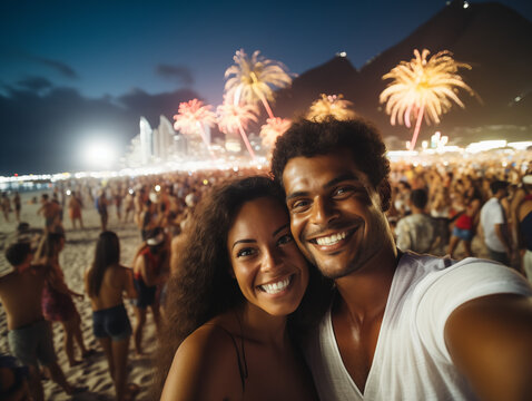 Casal comemorando a noite de ano novo na praia assistindo os fogos de artifício. Multidão na praia para o ano novo. 