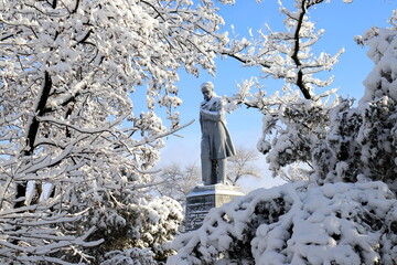 Winter in Ukraine. Monument to famous Ukrainian poet Shevchenko Taras among landscape. Trees covered with snow, winter weather. Dnipro city - obrazy, fototapety, plakaty
