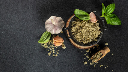 Basil salt is a natural spice with sea salt and fresh basil as seasoning on a dark background, Long banner format. top view. copy space for text