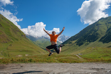 Mountain Gravity: A Man's Soaring Jump Against a Canvas of Greenery