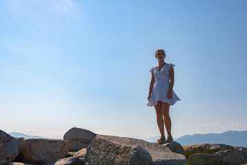 Seaside Elegance: A Girl in a White Dress on the Blue Sea