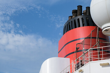 Red and black funnel of classic ocean liner cruise ship cruiseship against deep blue sky during...