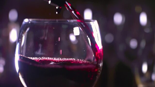 Red wine is beautifully poured into a glass. A bartender pours red wine into a glass. Production and sale of wine. 