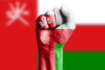 Man hand fist of OMAN flag painted. Close-up.