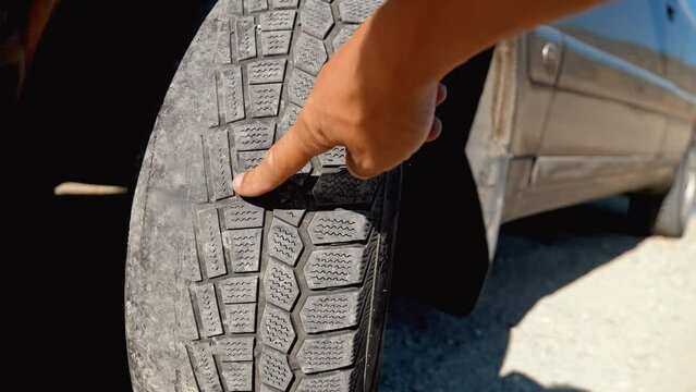 Finger of man's hand pointing at old, damaged and worn black tire tread of front wheels. Change Time. Tyre Tread Problems and Solution Concept. Camber and toe. tracking or alignment of wheels