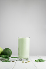 Green detox smoothie, blended vegetarian drink in a glass from spinach, apple, avocado and seeds on...