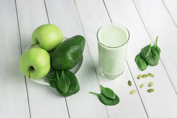 Green detox smoothie, blended vegetarian drink in a glass from spinach, apple, avocado and seeds on...
