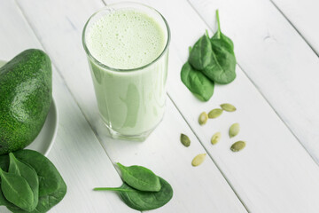Green detox smoothie, blended vegetarian drink in a glass from spinach, apple, avocado and seeds on...