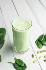 Green detox smoothie, blended vegetarian drink in a glass from spinach, apple, avocado and seeds on...