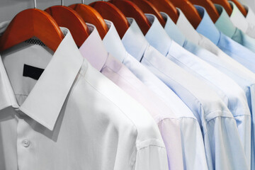 Obraz premium Closeup photo of Men's shirts hanging. Clothes hang on a shelf . Cloth Hangers with Shirts. Men's business clothes