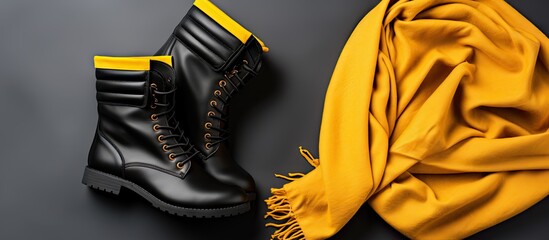 Women fashionable black leather ankle boots on mustard scarf Flat lay top view. Copyspace image. Header for website template