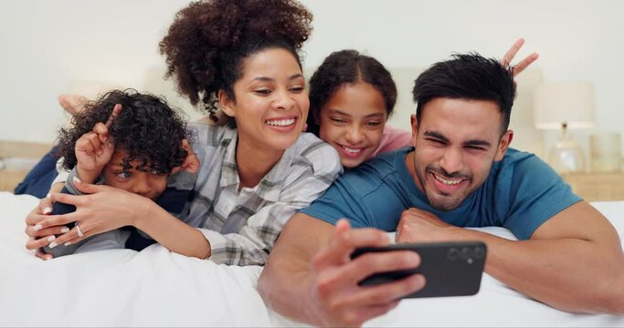 Happy family, love and bed selfie in a house with fun, games or peace hands for photography, memory or bonding. Bedroom, profile picture and children with parents, v sign or smile for social media