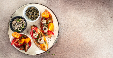 Tapas with anchovies and tomatoes on a blue background, Long banner format. top view - obrazy, fototapety, plakaty