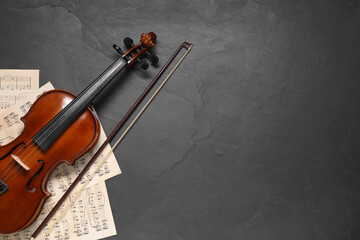 Violin, bow and music sheets on black table, top view. Space for text