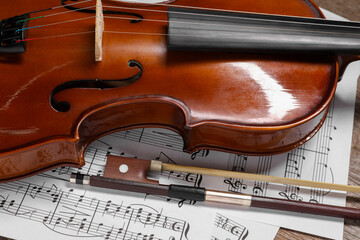 Violin, bow and music sheets on wooden table, closeup