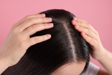 Naklejka premium Woman examining her hair and scalp on pink background, closeup