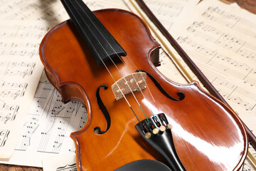 Fototapeta na wymiar Violin, bow and music sheets on table, closeup