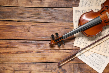 Violin, bow and music sheets on wooden table, top view. Space for text