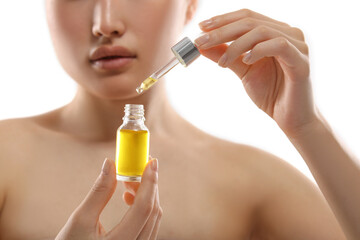 Fototapeta premium Beautiful young woman with bottle of cosmetic serum on white background, selective focus