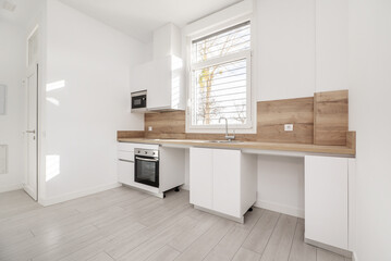 Furnished kitchen without appliances, recently installed in a loft-type home with a window in the middle