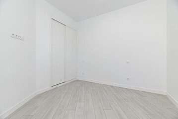 An empty room in a loft-style home with a two-section built-in wardrobe with white wooden sliding...