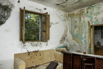 Room in an abandoned building with walls in poor condition and destroyed furniture lying on the...