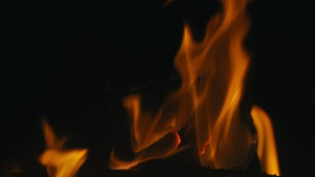 Une cheminée confortable et relaxante. Gros plan, flammes du feu. Feu de nuit, bûches sont en feu, étincelles volent. 4k, ralenti