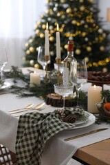 Christmas table setting with festive decor and dishware in room