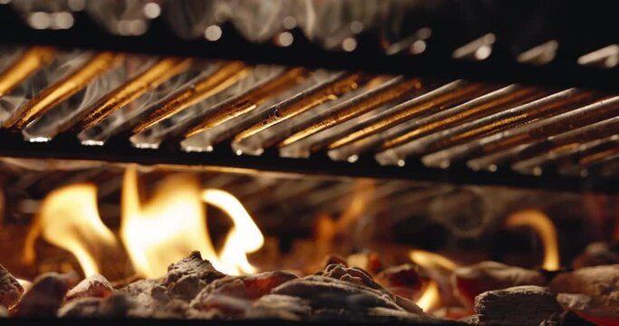 Black iron barbecue grill filled with burning coal. Hot coals with blazing flame under grill grate fascinated with their beauty. Glowing coal and fire sparks, copy space. Most delicious grilled dishes