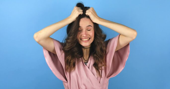 Happy woman looking camera shocked surprised say wow put hands on face, touch her hair. Wow, it is awesome. Surprised girl face. Close up of shocked woman face expression isolated on blue background.