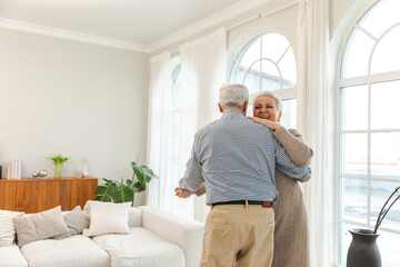 Keep moving. Romantic senior mature couple dancing to music together at home. Happy smiling family...